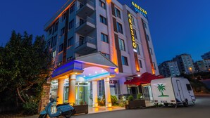 A multi-story hotel with a prominent sign, a covered entrance, and a parked scooter.