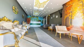 A hotel lobby with a reception desk, plush seating, and a large wall mural.