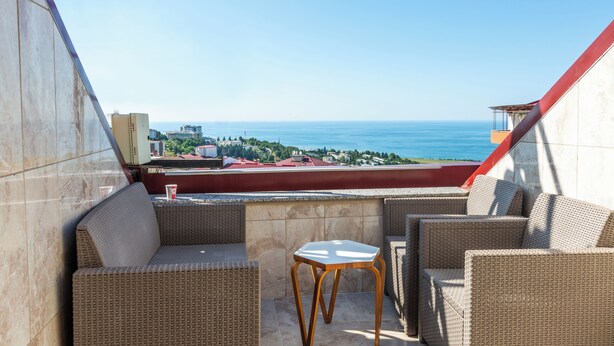 A balcony with wicker furniture and a view of the sea.