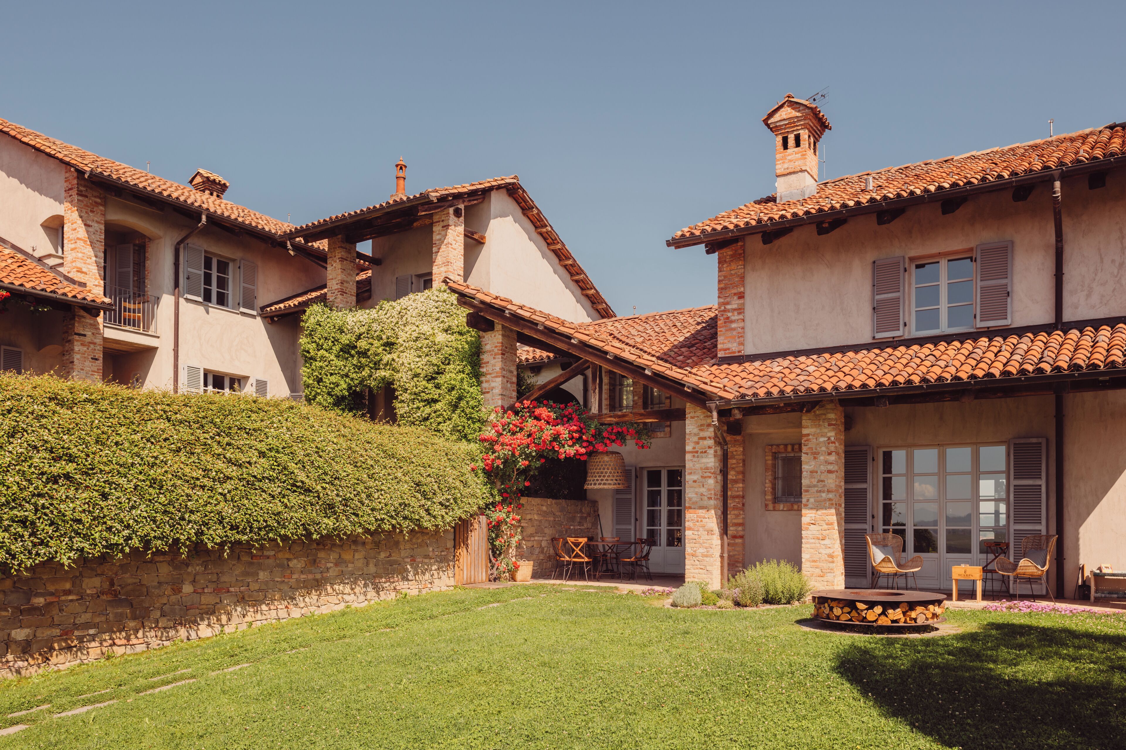 A two-story house with a tiled roof, a stone wall, and a well-maintained lawn.
