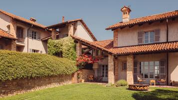A two-story house with a tiled roof, a stone wall, and a well-maintained lawn.
