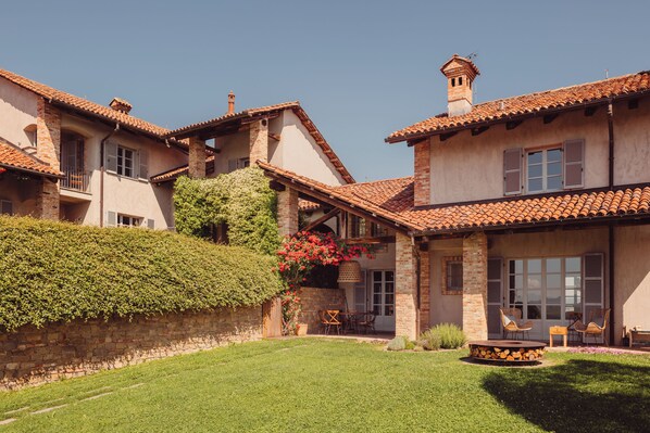 A two-story house with a tiled roof, a stone wall, and a well-maintained lawn.