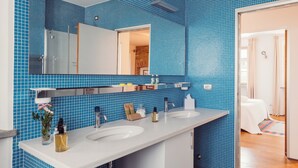 A bathroom with blue tiled walls, a white sink, and a mirror. - Scarpa Villas (Piemonte)