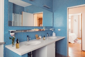 Un baño con paredes de azulejos azules, un lavabo blanco y un espejo.