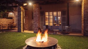 A patio with a fire pit, outdoor furniture, and a stone wall. - Scarpa Villas (Piemonte)