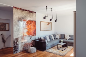 A modern living room with a grey sofa, black side table, and a patterned rug. - Scarpa Villas (Piemonte)