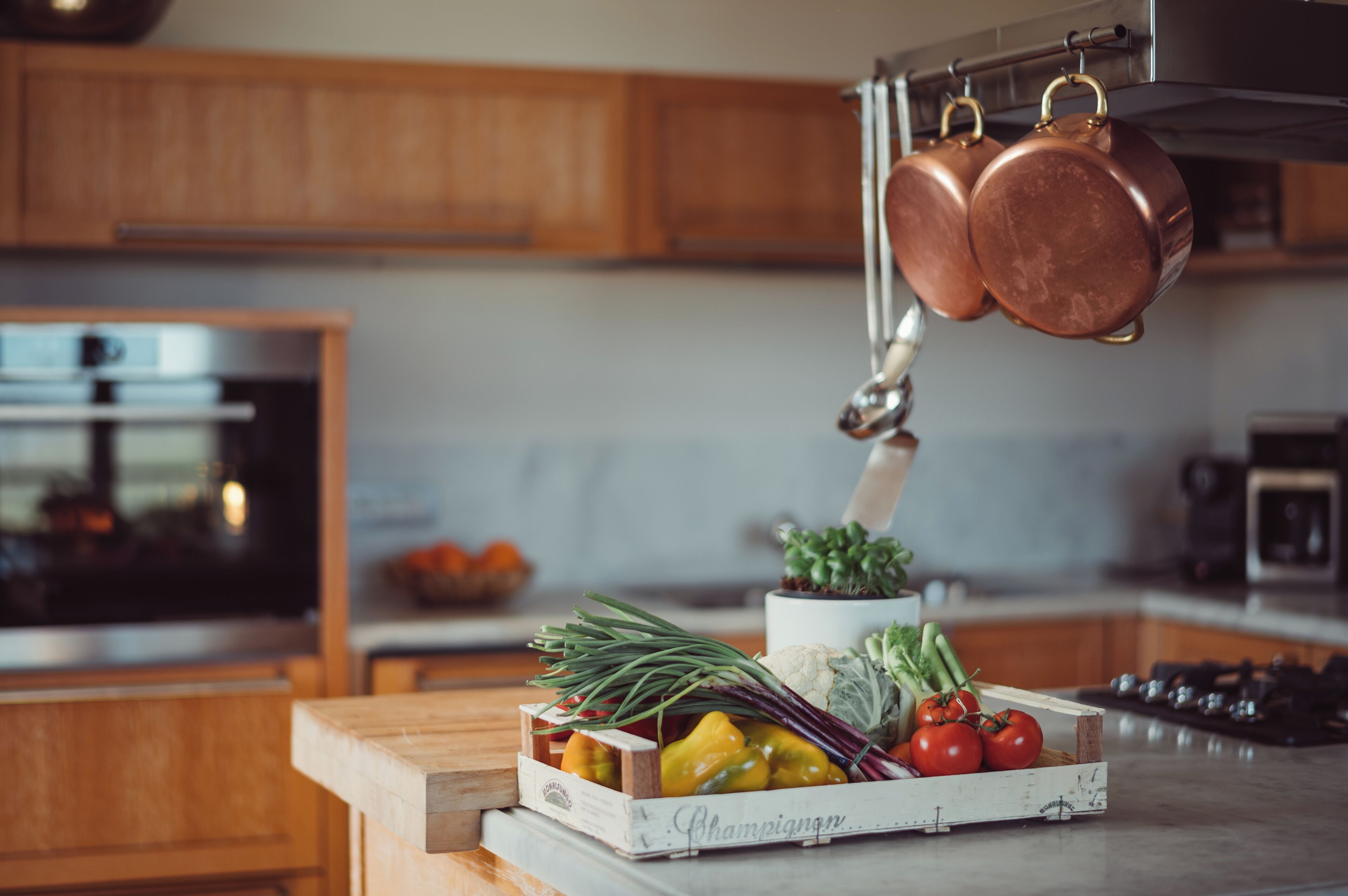 Une cuisine avec des meubles en bois, un four en acier inoxydable et un porte-casseroles suspendu.
