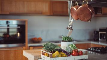 Une cuisine avec des meubles en bois, un four en acier inoxydable et un porte-casseroles suspendu.