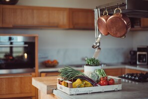A kitchen with wooden cabinets, a stainless steel oven, and a hanging pot rack. - Scarpa Villas (Piemonte)