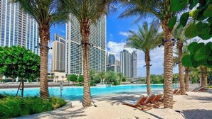Ein Strand mit Palmen, einem Pool und Hochhäusern im Hintergrund.