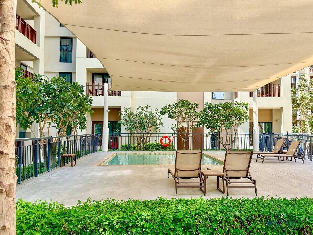 A poolside area with lounge chairs, a pool, and a covered seating area.