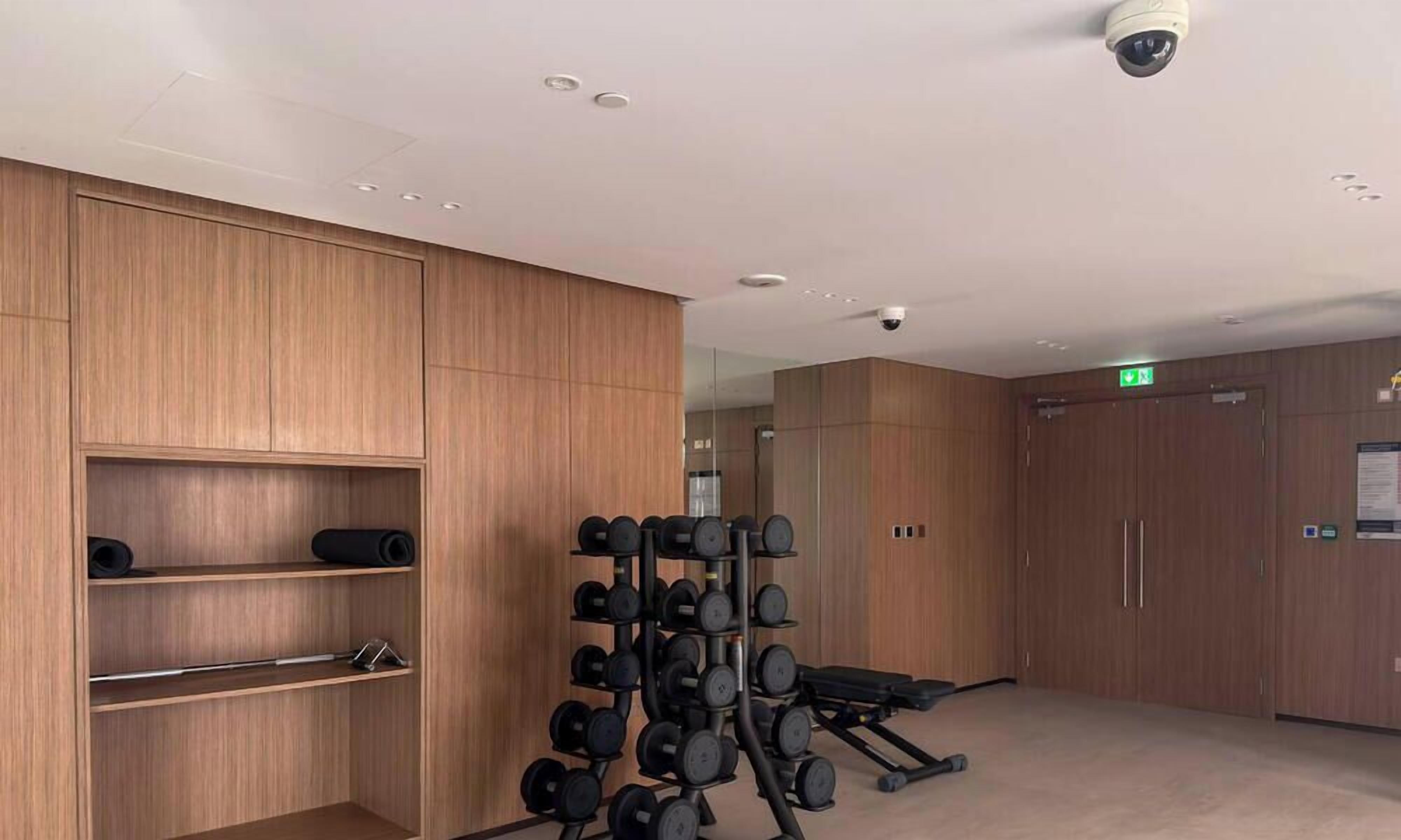 Ein Fitnessraum mit Holzausbau, Hantelständer und Trainingsgeräten.