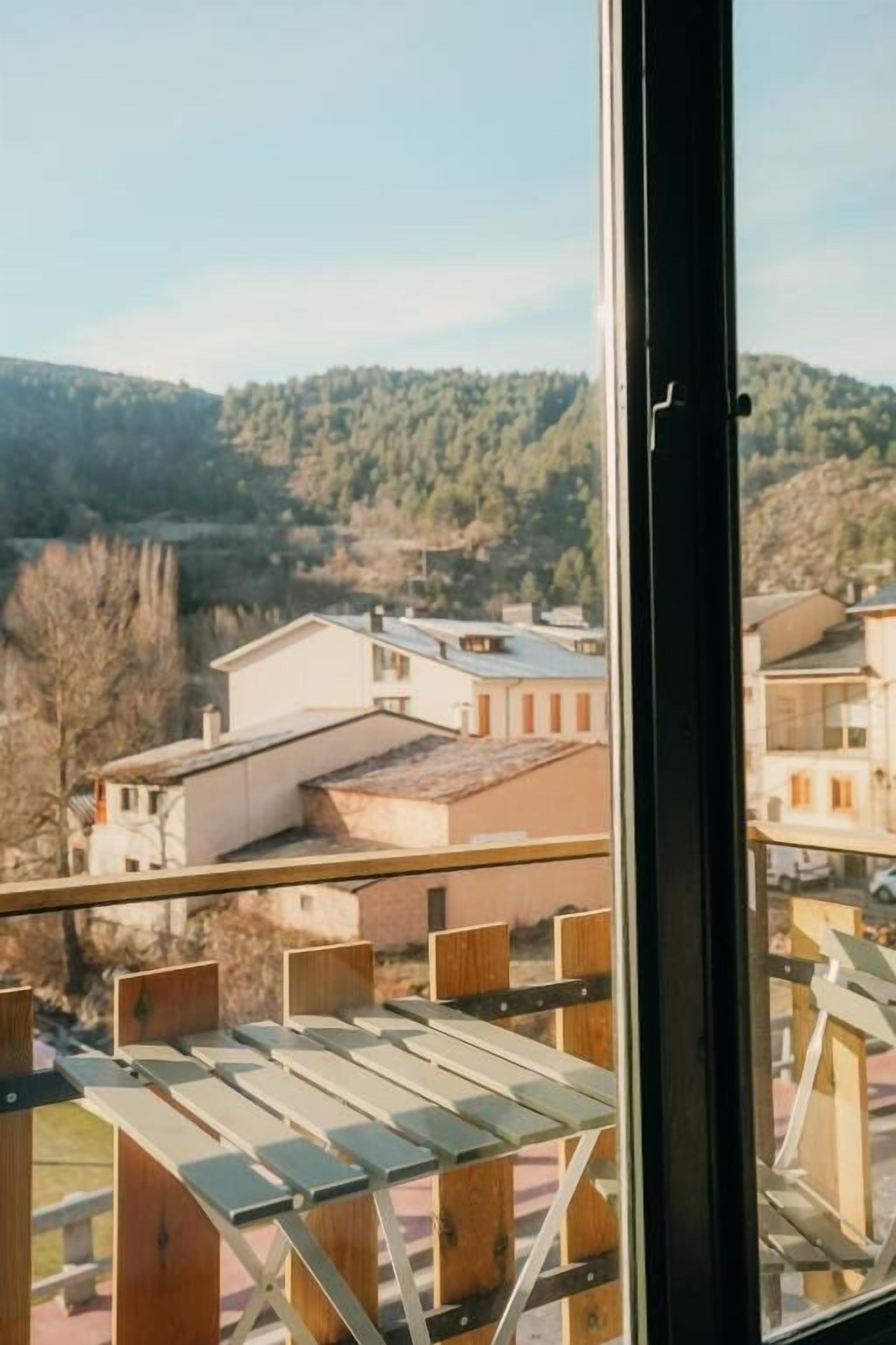 Vista desde un balcón con baranda metálica, sobre una zona residencial con casas y árboles.