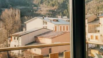 Vista desde un balcón con baranda metálica, sobre una zona residencial con casas y árboles.