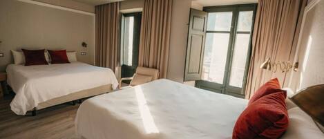 A hotel room with two beds, a ceiling fan, large windows with curtains, and a view of the city.