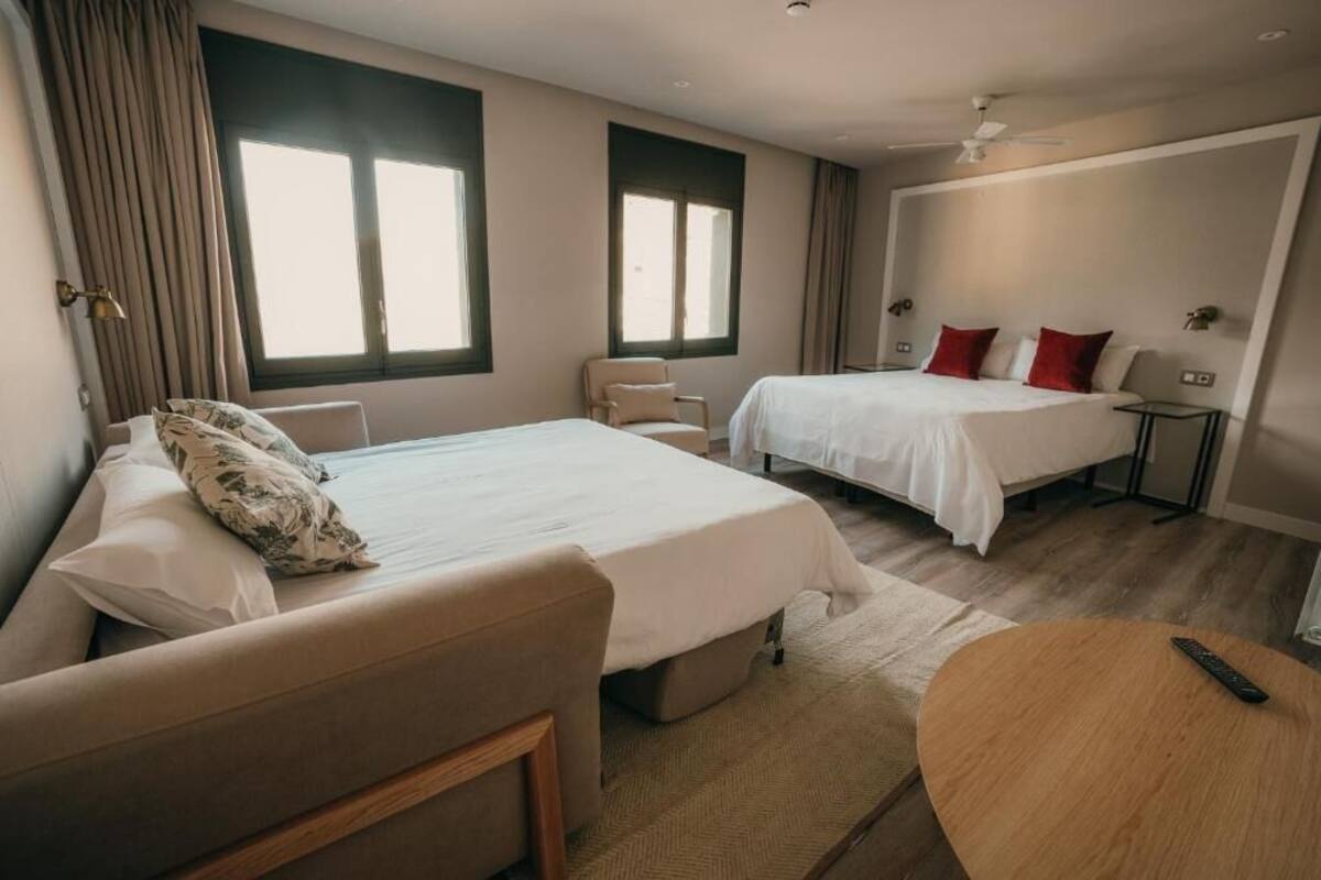 A hotel room with a bed, a chair, a round table, and a nightstand.