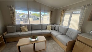 A modern living area with a sectional sofa, a wooden coffee table, and a kitchenette. - Sleeps 8 - Skegness - Tv (Skegness)