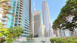 Un horizonte urbano moderno con rascacielos, una piscina en la azotea y abundante vegetación.