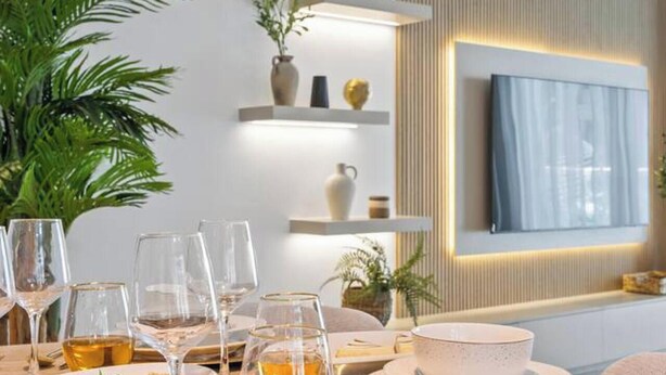 A dining area with a table set for a meal, a potted plant, and shelves with decorative items. - Mediterranean Prestige 2BR | Sulafa Tower, Marina (Dubai)