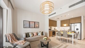 Ein modernes Wohnzimmer mit Sofa, Sessel, Couchtisch und Kunstwerk an der Wand.