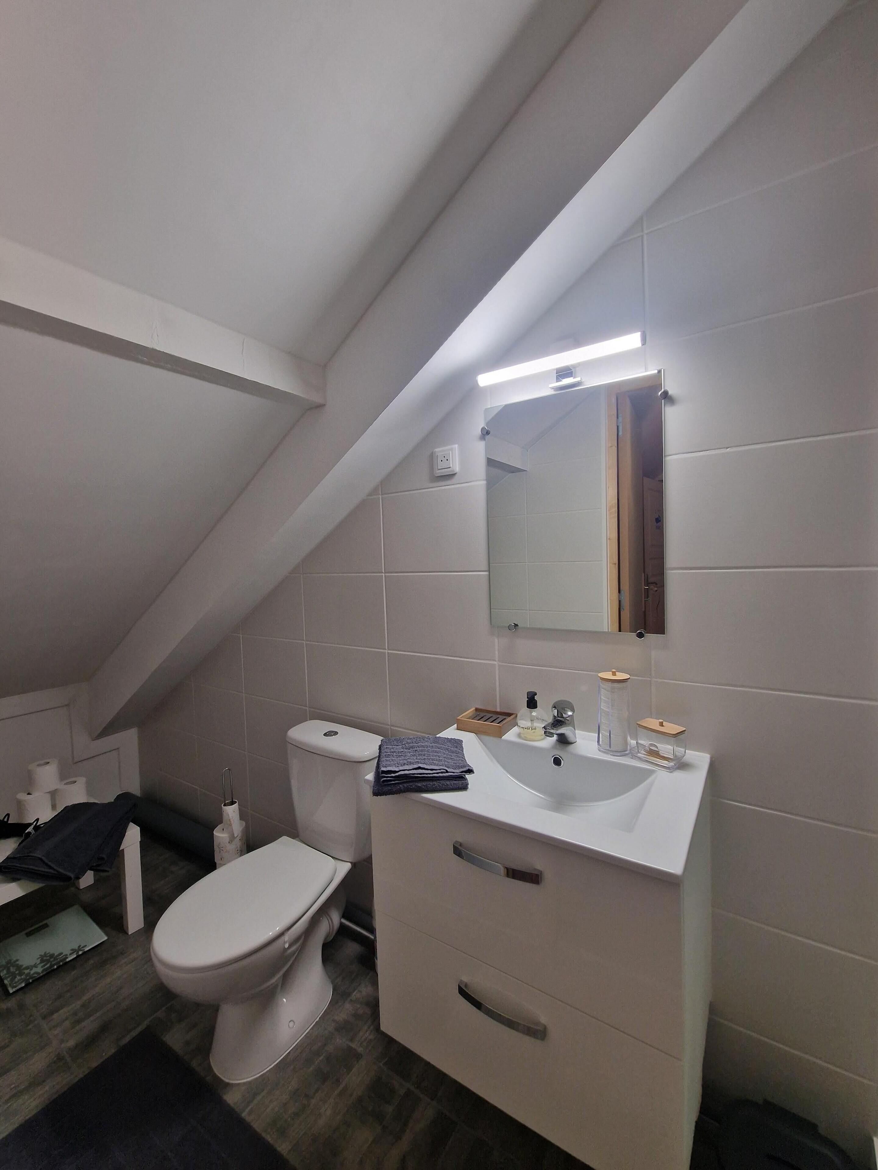 Een moderne badkamer met toilet, wastafel en spiegel.