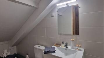Een moderne badkamer met toilet, wastafel en spiegel.
