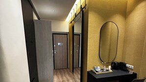 A hotel room with a wooden floor, a desk with a mirror, a chair, and a small table with toiletries. - Syntagma Divine Guestrooms (Athens)