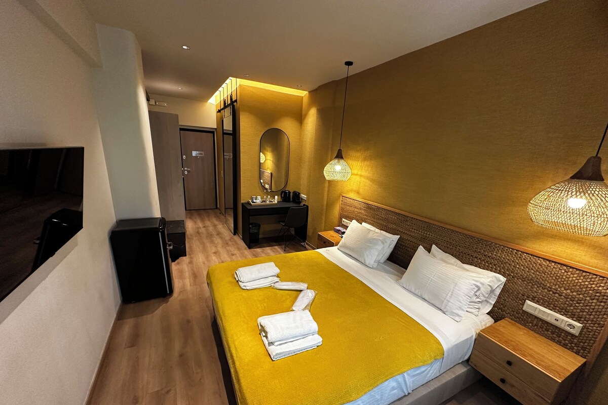 Una habitación de hotel con cama, mesita de noche, lámpara y espejo en la pared.