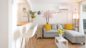 Una sala de estar moderna con un sofá, una mesa de centro y una zona de comedor con sillas.