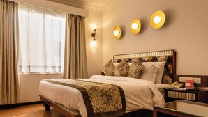 Ein Hotelzimmer mit Bett, Nachttisch, Lampe und einem Fenster mit Vorhängen.