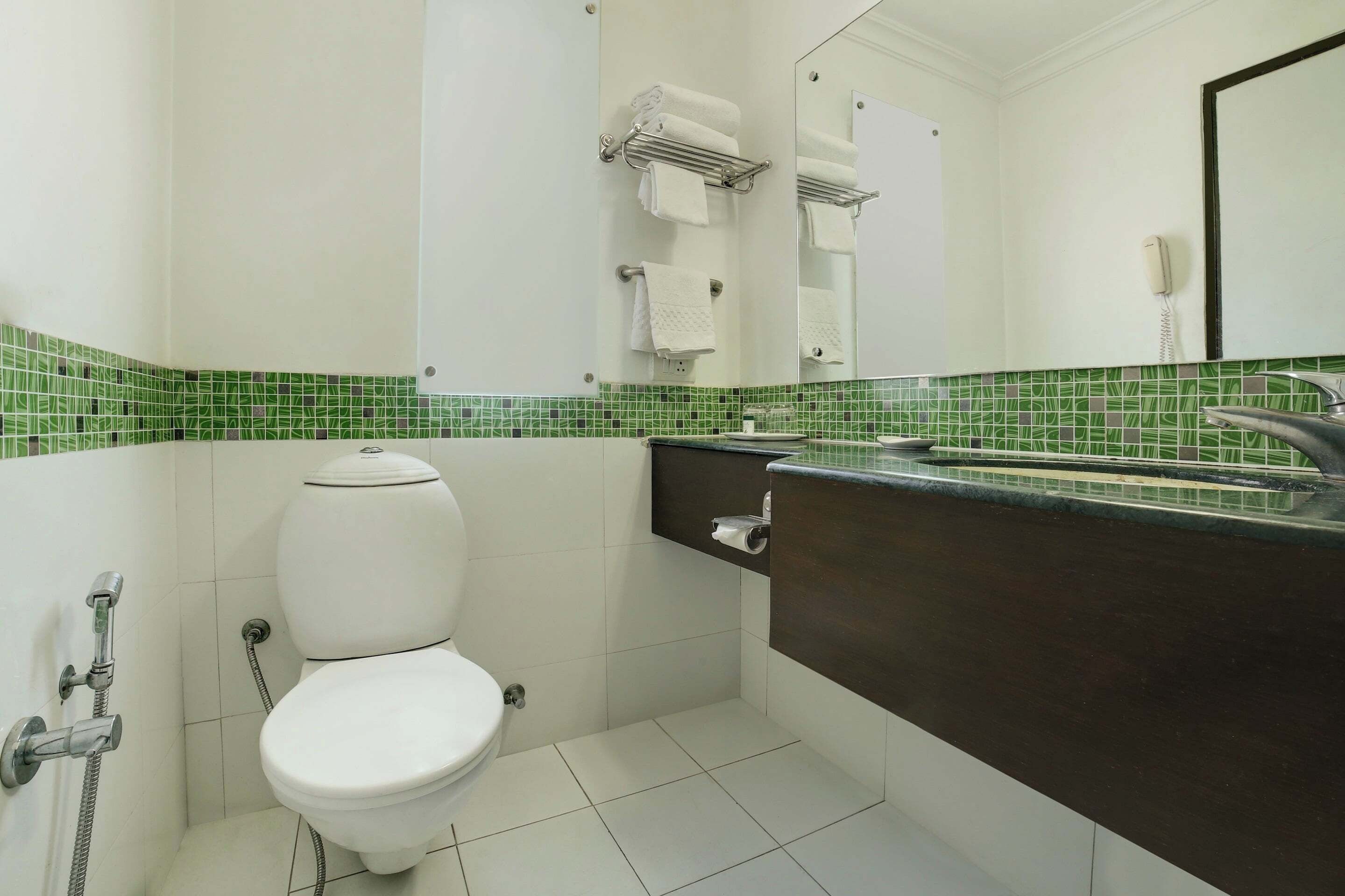 Een badkamer met toilet, douche, wastafel en spiegel.