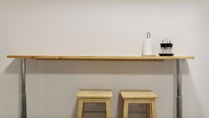 Una habitación minimalista con una mesa de madera, dos taburetes y un pequeño objeto decorativo sobre la mesa.