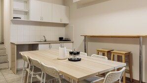 Una cocina moderna con armarios blancos, una mesa de comedor de madera y dos taburetes de madera.