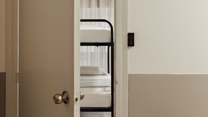 Una habitación con una litera, una puerta con pomo redondo y un interruptor de luz en la pared.