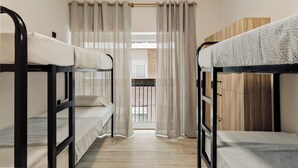 Un dormitorio con literas, un armario de madera y una ventana con cortinas.