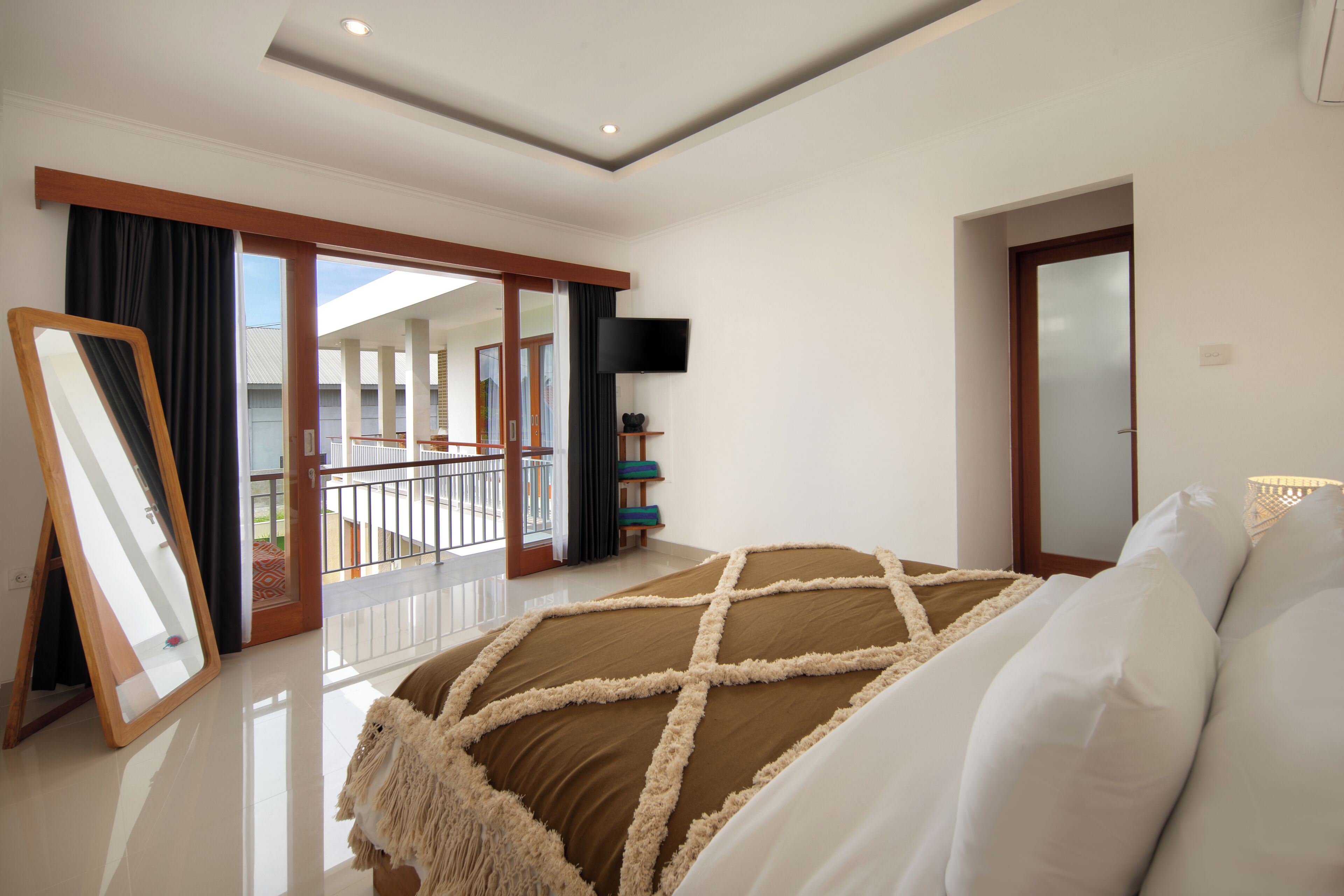 Ein Schlafzimmer mit einem großen Bett, einem Fernseher, einem Balkon mit Aussicht und einer Schiebetür.