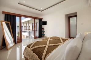 Ein Schlafzimmer mit einem großen Bett, einem Fernseher, einem Balkon mit Aussicht und einer Schiebetür.