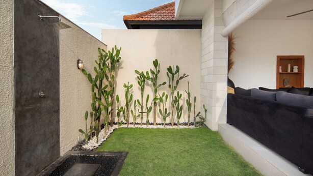 A modern outdoor area with a concrete shower, green artificial grass, and a black sofa. - Villa Cinta Rose (Badung)