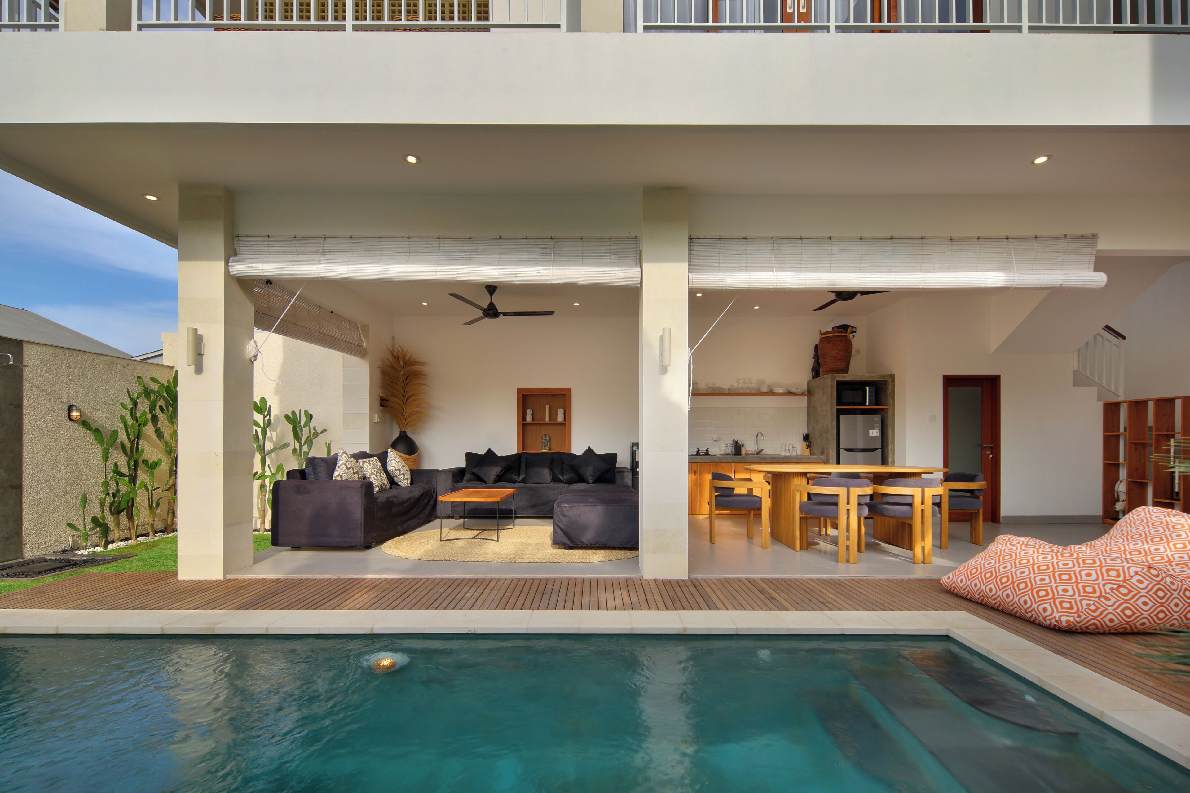 Un espacio exterior moderno con piscina, zona de comedor y un conjunto de asientos.
