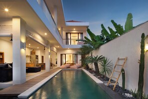 A modern house with a swimming pool, a wooden deck, and a balcony overlooking the pool. - Villa Cinta Rose (Badung)