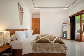 Une chambre à coucher comprenant un lit, une table de chevet, une lampe, une armoire en bois et un grand miroir.