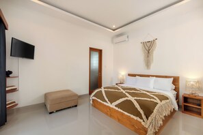 Ein Schlafzimmer mit einem Bett, einem Fernseher, einer Bank, einer Wand-Klimaanlage und einer Tür.
