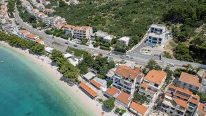 An aerial view of a coastal town with a beach, residential buildings, and a road. - Villa LUX 55 Tucepi (Tučepi)