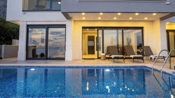 A modern two-story building with a swimming pool, sun loungers, and a glass door entrance. - Villa LUX 55 Tucepi (Tučepi)