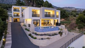 A modern two-story house with a swimming pool, a driveway, and a view of the surrounding landscape. - Villa LUX 55 Tucepi (Tučepi)