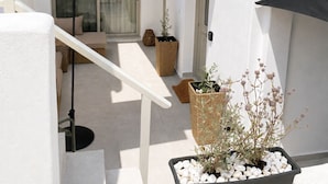 Un edificio blanco con un área de asientos cubierta al aire libre, una escalera y plantas en macetas.