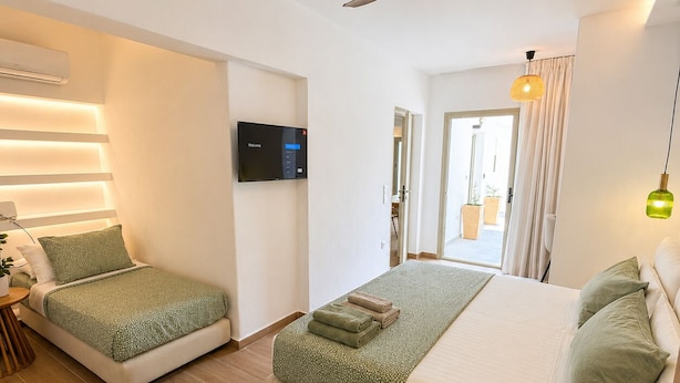 Una habitación de hotel moderna con una cama grande, una cama más pequeña, un ventilador de techo, un televisor y vistas al exterior.