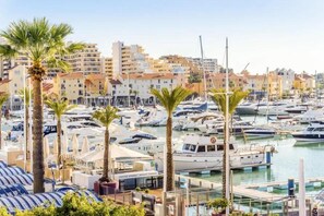 A marina with numerous boats docked, surrounded by buildings and palm trees. - Villa Gemini in Guia (Albufeira)