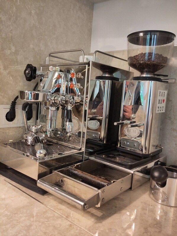 A commercial espresso machine with multiple portafilters, a coffee grinder, and a milk frothing station.
