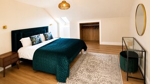 A bedroom with a bed, a nightstand, a dresser, a mirror, and a walk-in closet.